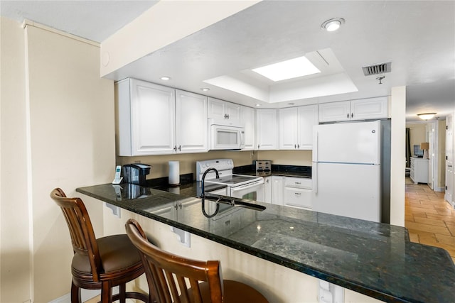 kitchen featuring white cabinetry, white appliances, a raised ceiling, and kitchen peninsula