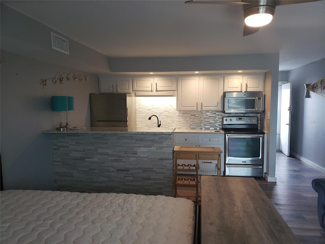 kitchen featuring white cabinetry, backsplash, ceiling fan, stainless steel appliances, and dark hardwood / wood-style flooring