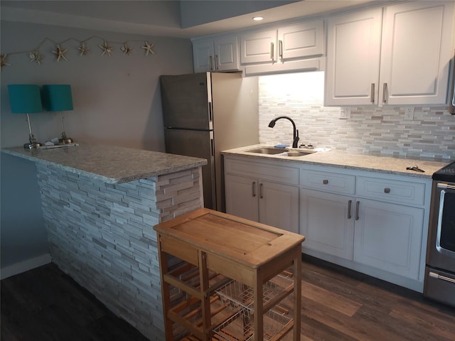 kitchen featuring light stone countertops, sink, white cabinets, tasteful backsplash, and dark hardwood / wood-style flooring