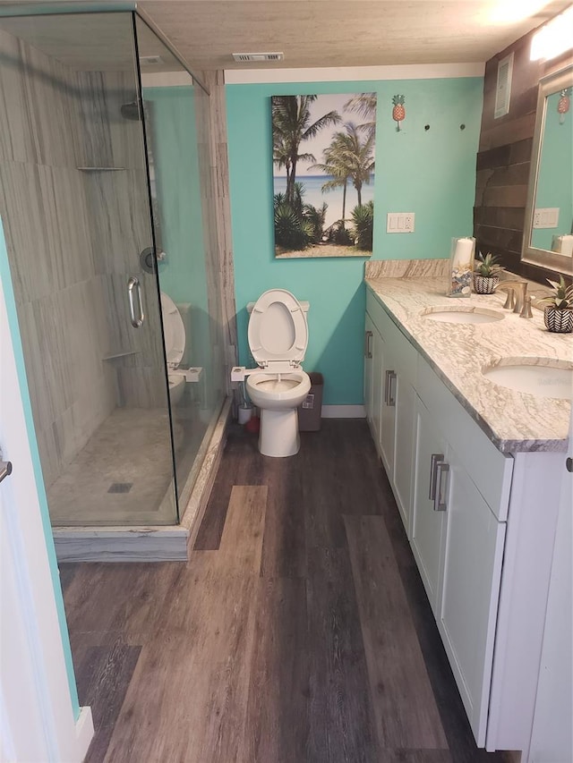 bathroom featuring walk in shower, toilet, double vanity, and hardwood / wood-style flooring