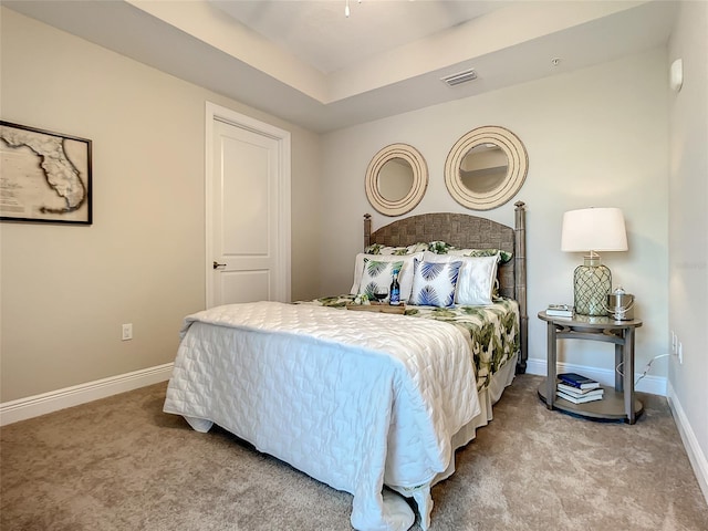 bedroom featuring light carpet and a tray ceiling