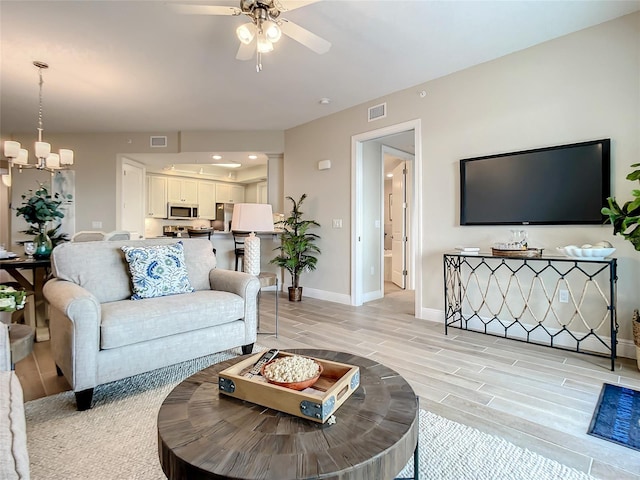 1 Riverwalk Dr Unit 302, New Smyrna Beach, FL 32169 - living room with visible vents, baseboards, ceiling fan with notable chandelier, and wood finish floors