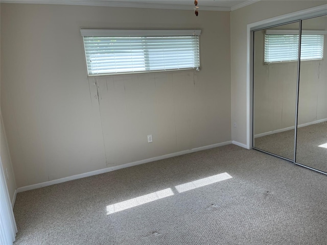 unfurnished bedroom featuring crown molding, a closet, and light colored carpet