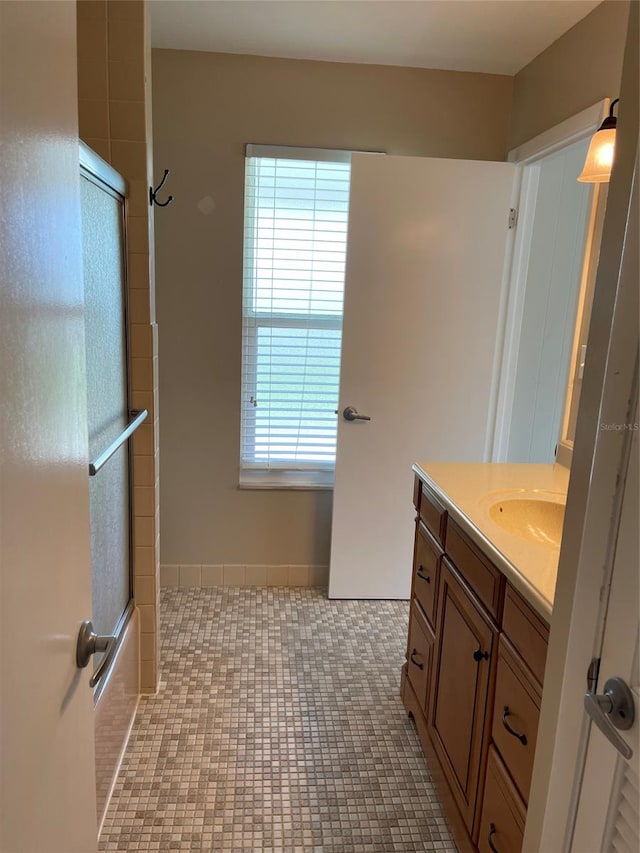 bathroom with plenty of natural light, combined bath / shower with glass door, tile floors, and vanity