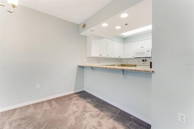 kitchen featuring a breakfast bar, white cabinetry, light carpet, kitchen peninsula, and white appliances