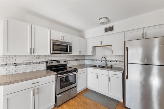 kitchen with white cabinetry, light hardwood / wood-style floors, and stainless steel appliances