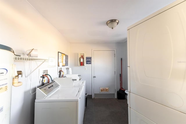 laundry room featuring hookup for a washing machine, dark tile floors, water heater, and washer and clothes dryer