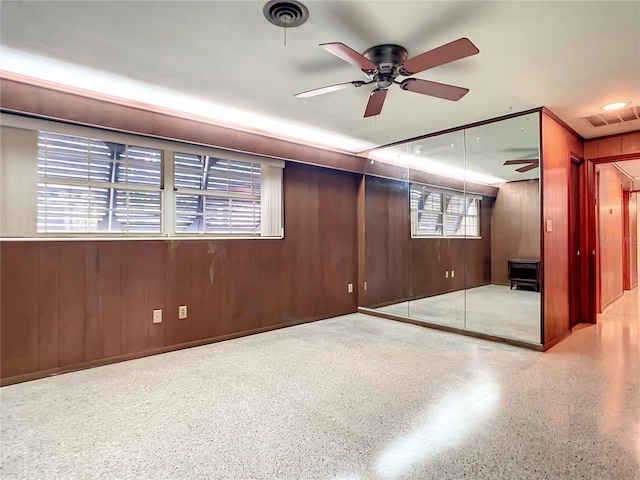 basement featuring ceiling fan and wood walls