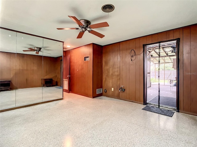 spare room featuring ceiling fan and wood walls