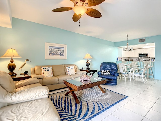 tiled living room with ceiling fan with notable chandelier