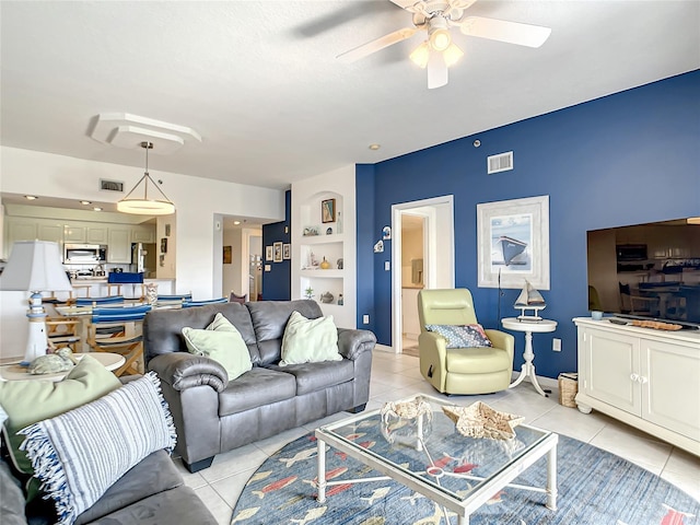 living room with built in shelves, ceiling fan, and light tile patterned flooring