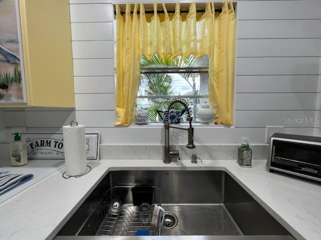 details with sink, wood walls, and light stone countertops