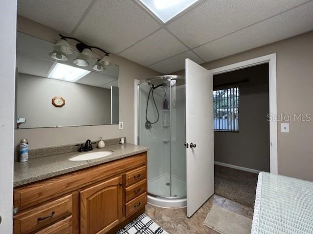 bathroom featuring a shower with door, a drop ceiling, and vanity