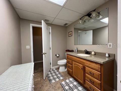 bathroom with toilet, vanity, and a paneled ceiling