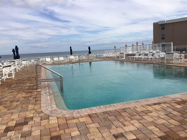 view of swimming pool with a water view and a patio area