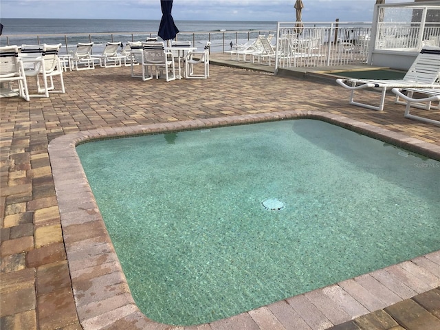 view of pool with a patio, a swimming pool, and a water view