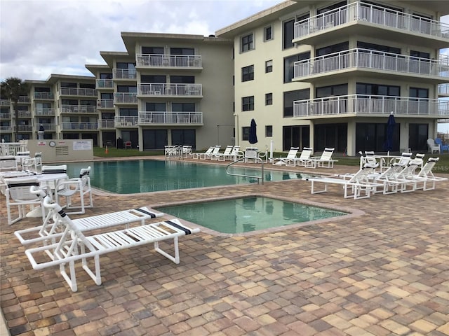 community pool with a community hot tub and a patio area