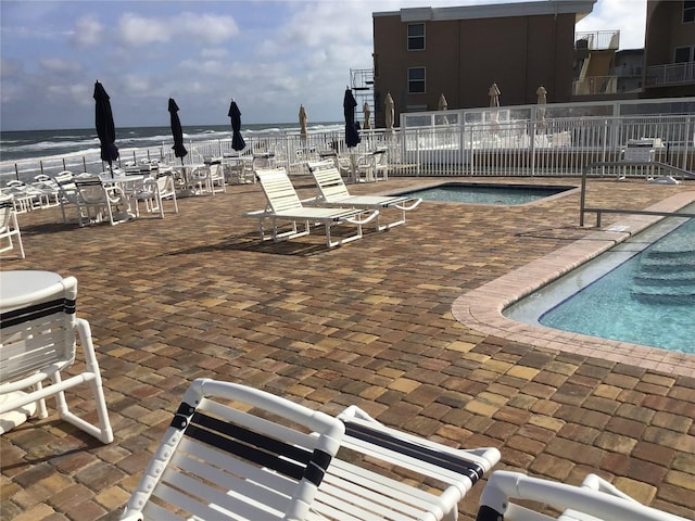 pool featuring a water view, fence, and a patio