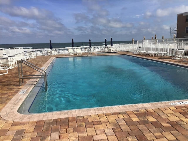 community pool with a water view and fence