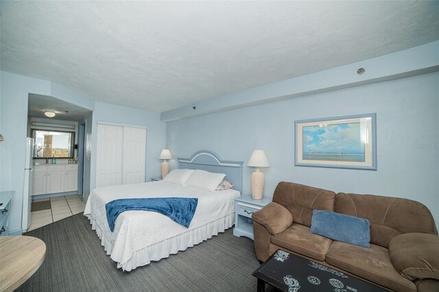 2700 N Atlantic Ave Unit 517, Daytona Beach, FL 32118 - bedroom with a closet, ensuite bathroom, freestanding refrigerator, and dark tile patterned floors