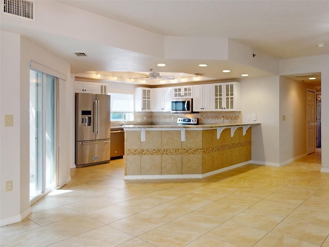 5300 S Atlantic Ave Unit 9201, New Smyrna Beach, FL 32169 - kitchen with ceiling fan, kitchen peninsula, tasteful backsplash, appliances with stainless steel finishes, and white cabinetry