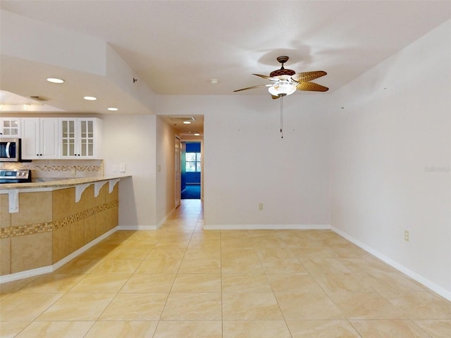 5300 S Atlantic Ave Unit 9201, New Smyrna Beach, FL 32169 - kitchen with white cabinets, tasteful backsplash, ceiling fan, and light tile flooring