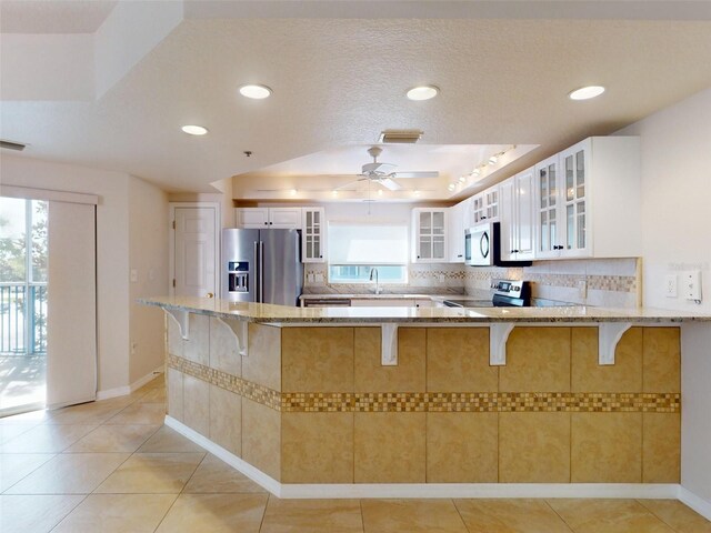 5300 S Atlantic Ave Unit 9201, New Smyrna Beach, FL 32169 - kitchen featuring stainless steel appliances, ceiling fan, kitchen peninsula, white cabinets, and light stone counters