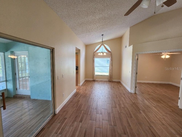 spare room with ceiling fan, a textured ceiling, high vaulted ceiling, and dark wood-type flooring