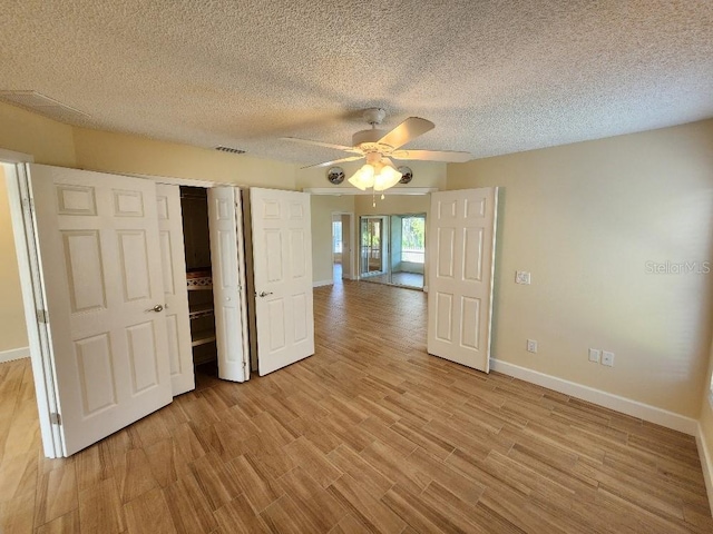 unfurnished bedroom with light hardwood / wood-style floors, ceiling fan, and a textured ceiling