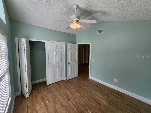 unfurnished bedroom featuring ceiling fan, dark wood-type flooring, a textured ceiling, a closet, and lofted ceiling