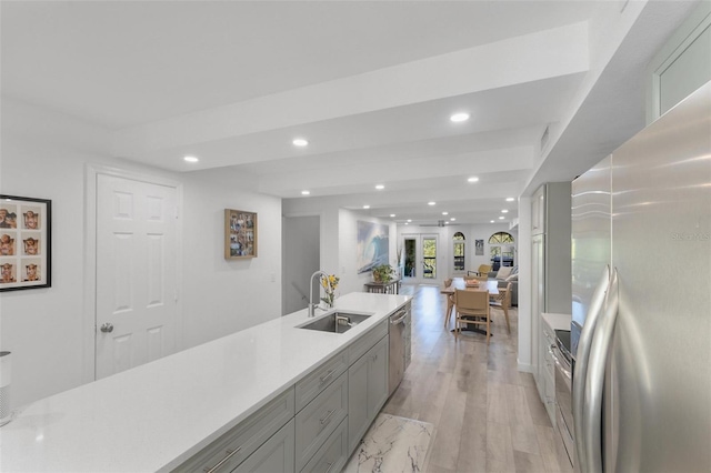 kitchen featuring appliances with stainless steel finishes, sink, gray cabinetry, and light hardwood / wood-style flooring