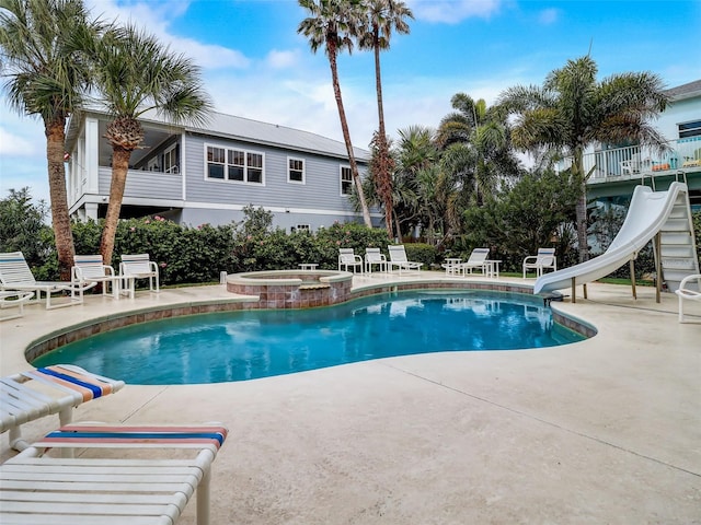 view of pool featuring a water slide, an in ground hot tub, and a patio