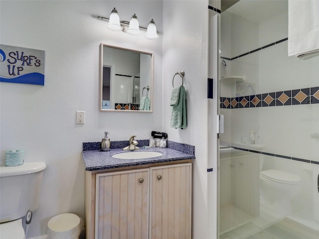 bathroom featuring vanity, a tile shower, and toilet