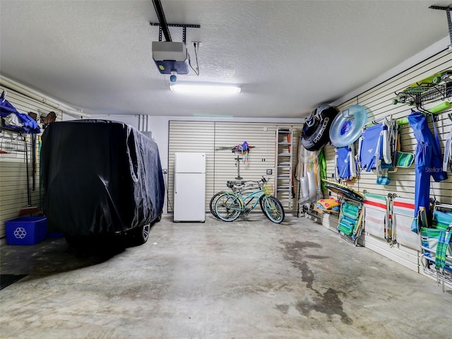 garage featuring white refrigerator and a garage door opener