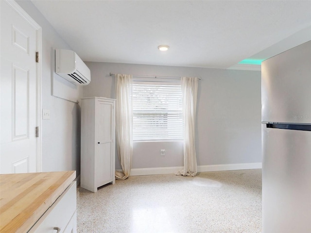 bedroom featuring a wall mounted AC and stainless steel refrigerator