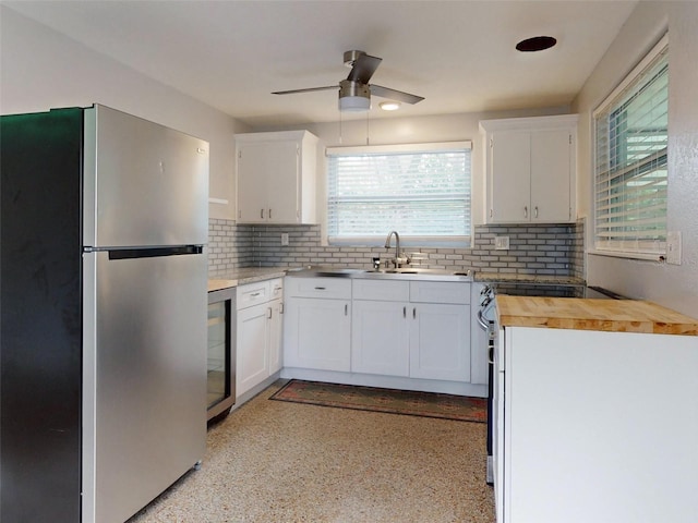 kitchen with white cabinetry, backsplash, ceiling fan, and stainless steel refrigerator