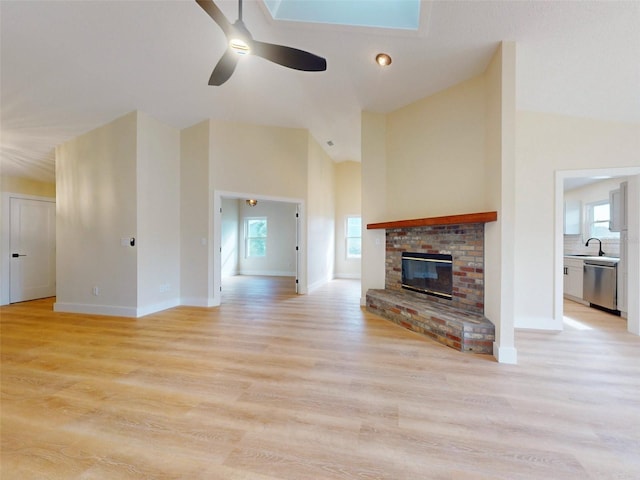 unfurnished living room with a fireplace, light wood-type flooring, ceiling fan, and lofted ceiling