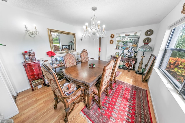 dining room with a textured ceiling, light hardwood / wood-style floors, and a chandelier