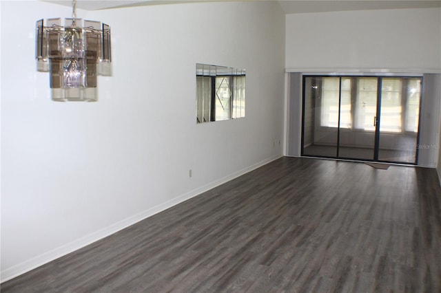 spare room with a chandelier, dark hardwood / wood-style floors, and a healthy amount of sunlight