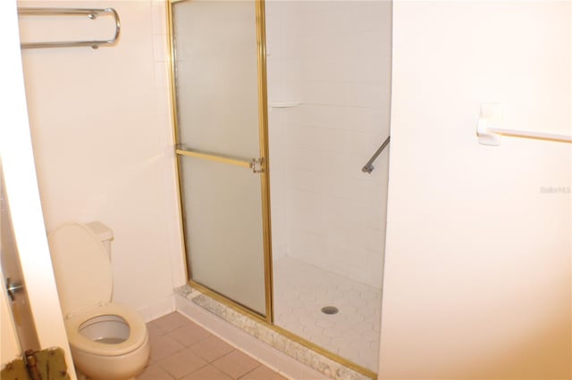 bathroom featuring tile patterned flooring, toilet, and walk in shower