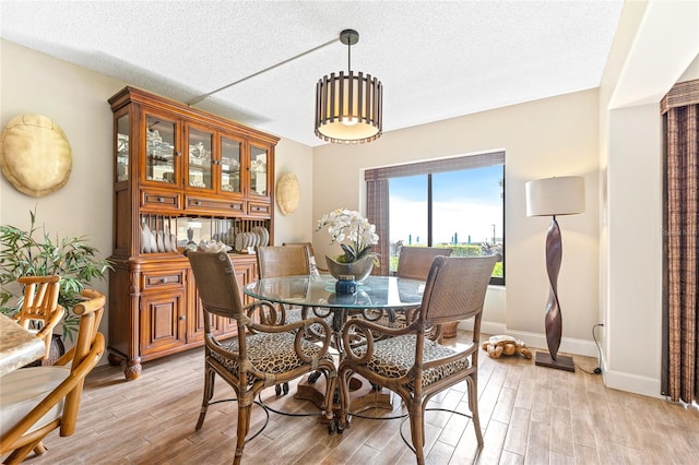 dining room with an inviting chandelier, a textured ceiling, and light wood-type flooring