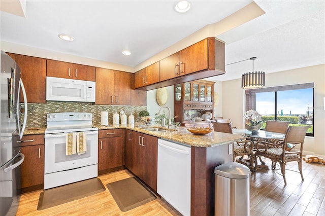 kitchen with pendant lighting, light hardwood / wood-style floors, tasteful backsplash, white appliances, and sink