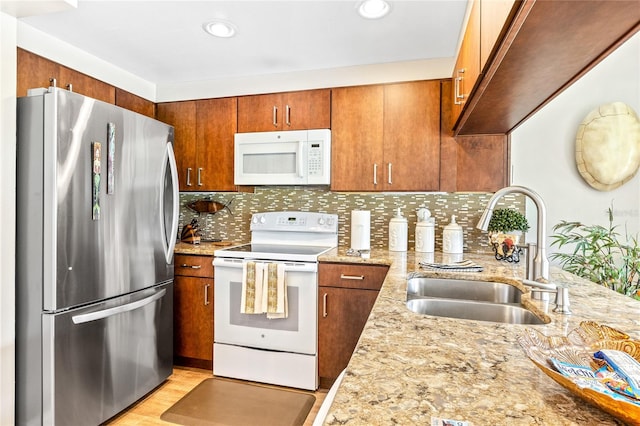 kitchen with white appliances, light stone countertops, tasteful backsplash, and sink