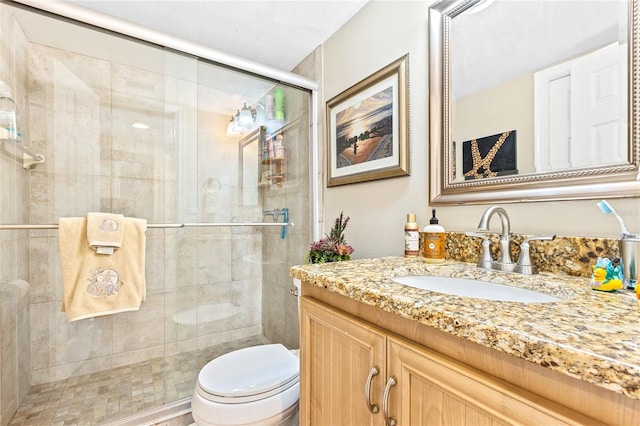 bathroom featuring toilet, vanity, and a shower with door