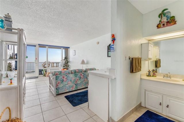 interior space with expansive windows, a textured ceiling, large vanity, and tile flooring