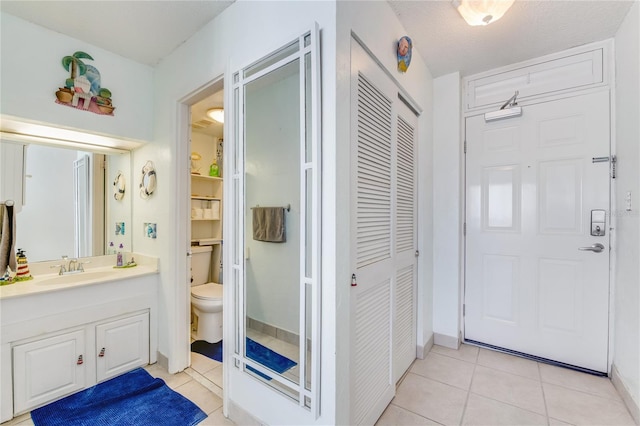 foyer with light tile floors, a textured ceiling, and sink