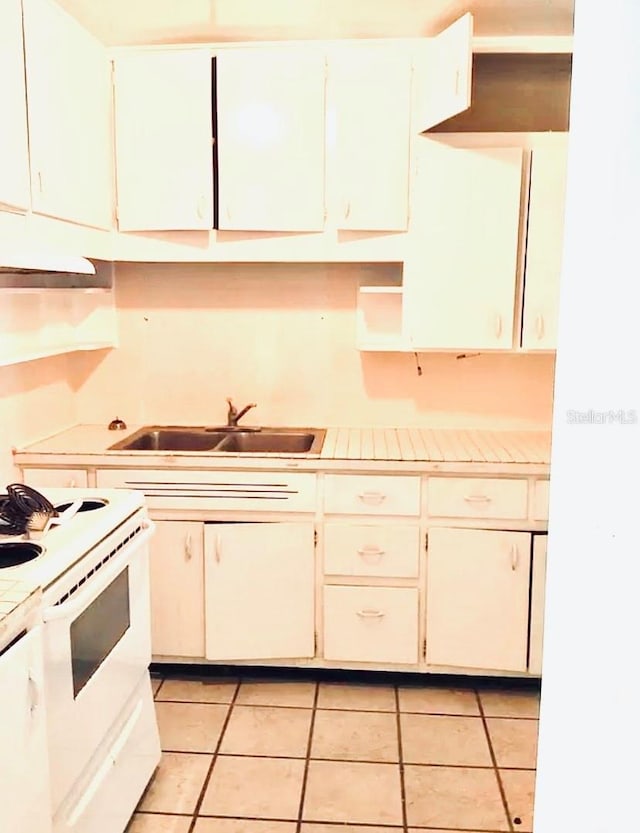 kitchen featuring white electric stove, sink, white cabinetry, and light tile floors