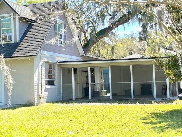 rear view of house with a lawn and a sunroom