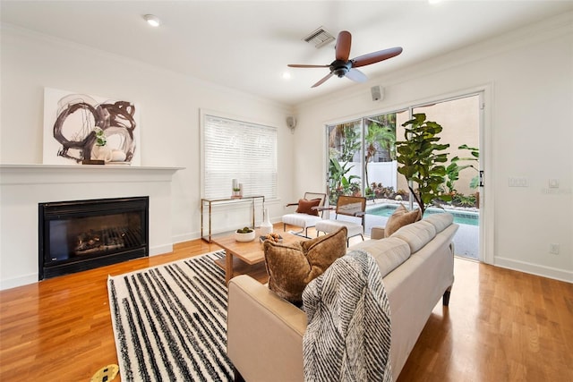 living room featuring light hardwood / wood-style flooring, ceiling fan, and ornamental molding