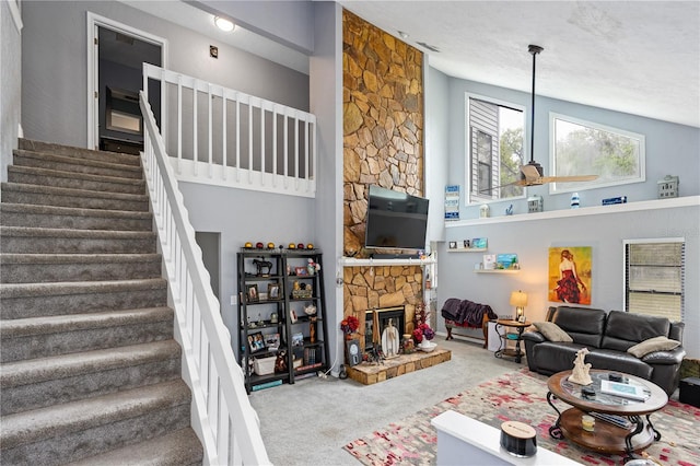 carpeted living room featuring a stone fireplace, ceiling fan, and lofted ceiling